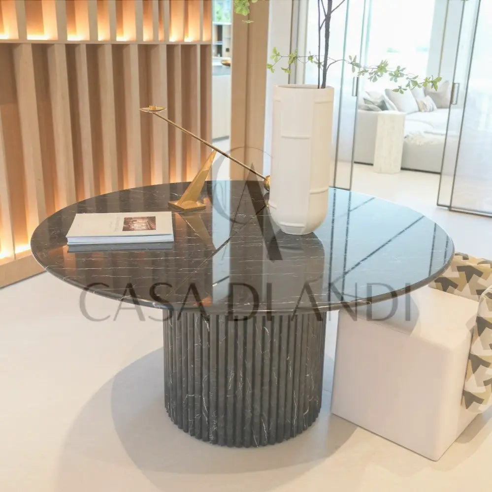 A luxurious round dining table made of black marquina marble with fluted leg design made in Dubai.