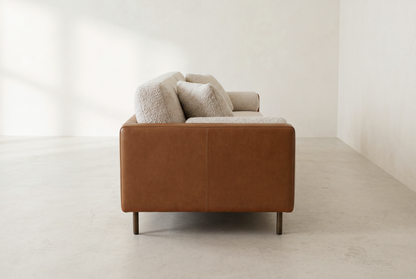 Sella sofa side view showing the slim leather arm and bronze legs
