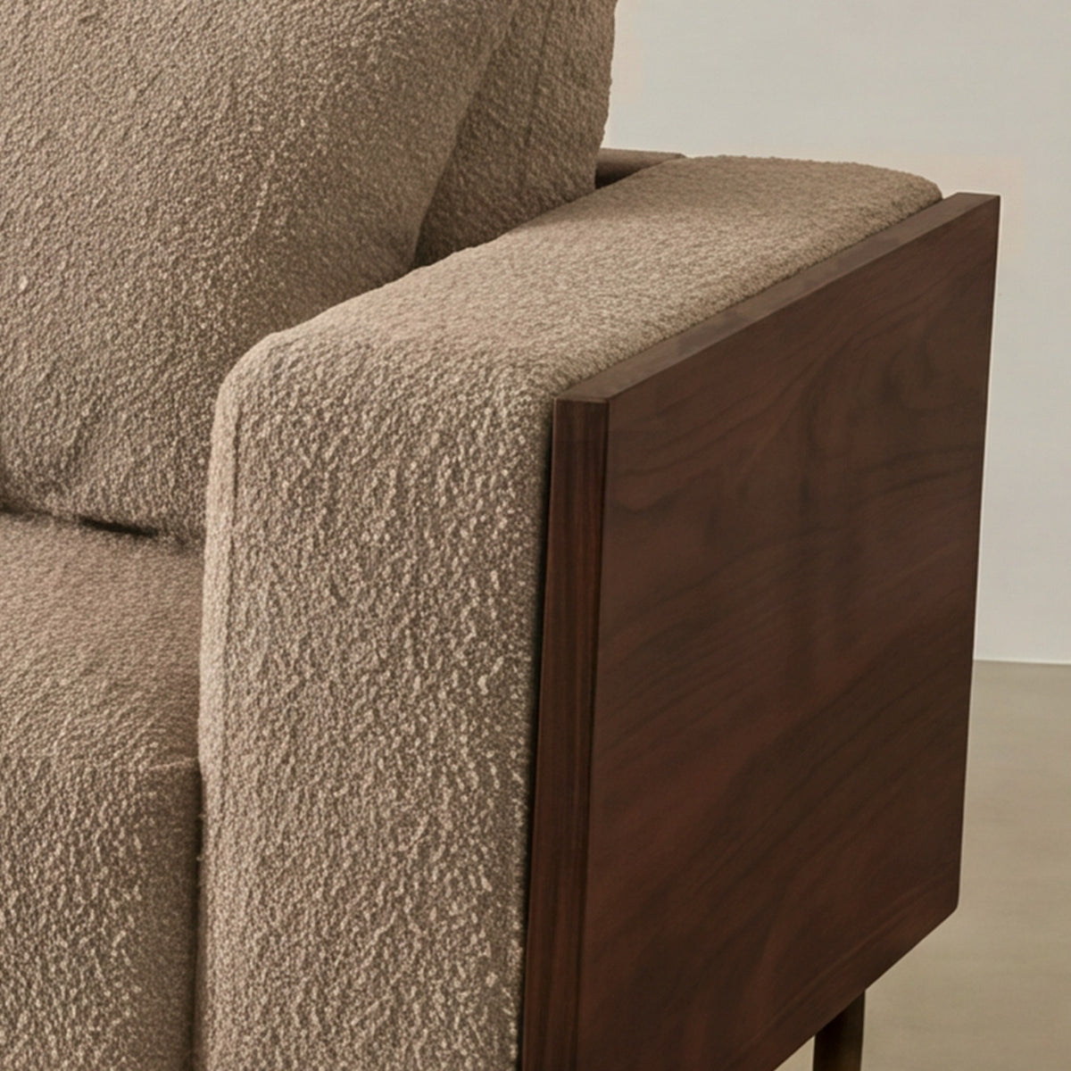 Close-up of the Cornice walnut-finish arm corner and bouclé cushion