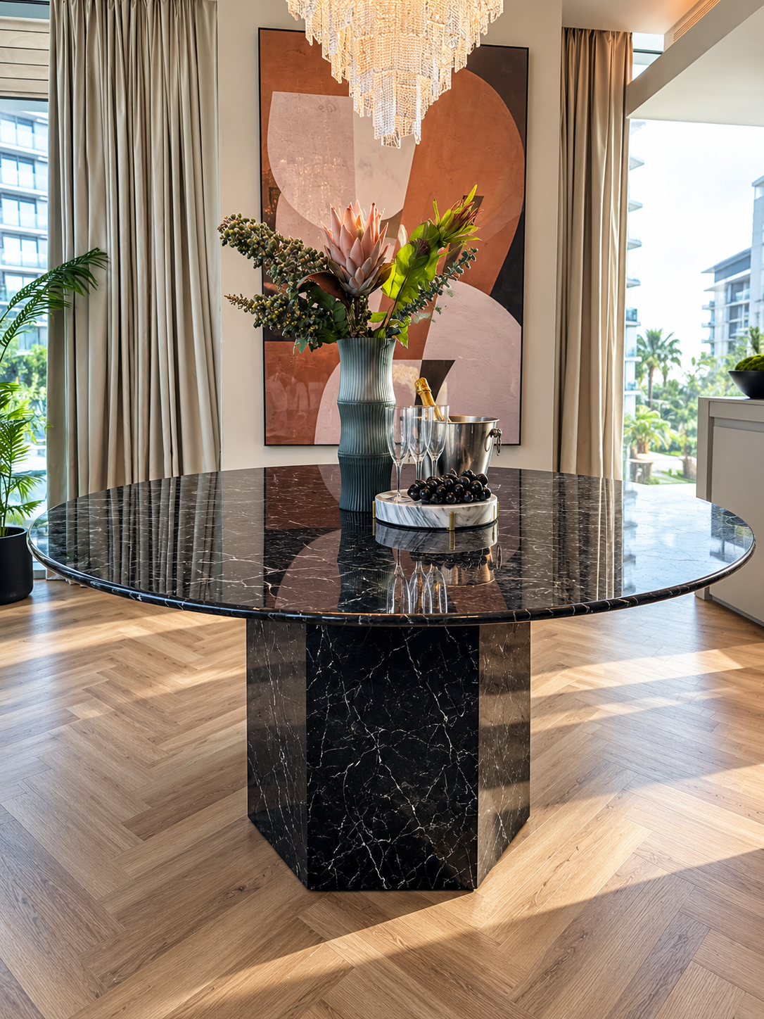Epico round dining table in Black Marquina marble on a hexagonal marble base, in a sunlit dining room with herringbone oak flooring