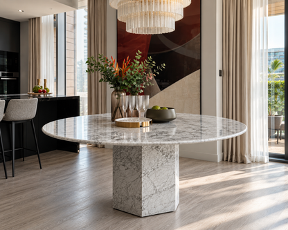 Epico round dining table in white Carrara marble in an open-plan dining room with a chandelier