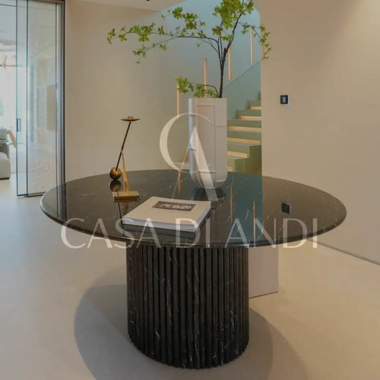 A luxurious round dining table made of black marquina marble with fluted leg design made in Dubai.
