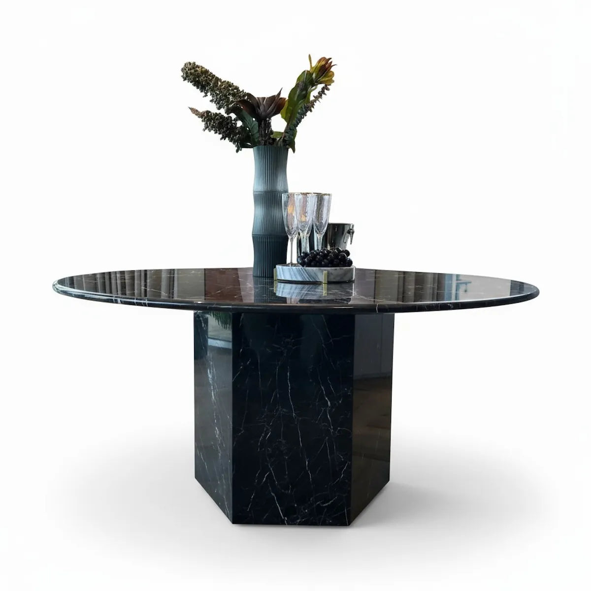 Black marble dining table with a vase of flowers and glasses on a white background