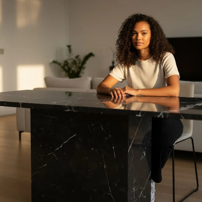 Woman sitting at a black marble table in a modern interior setting by Casa Di Andi Dubai